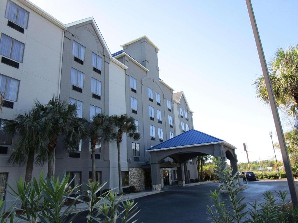 a hotel with palm trees in front of a building at Country Inn & Suites by Radisson, Murrells Inlet, SC in Myrtle Beach