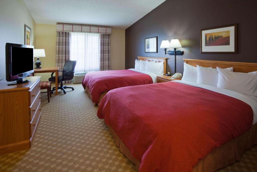 a hotel room with two beds and a flat screen tv at Country Inn & Suites by Radisson, Watertown, SD in Watertown