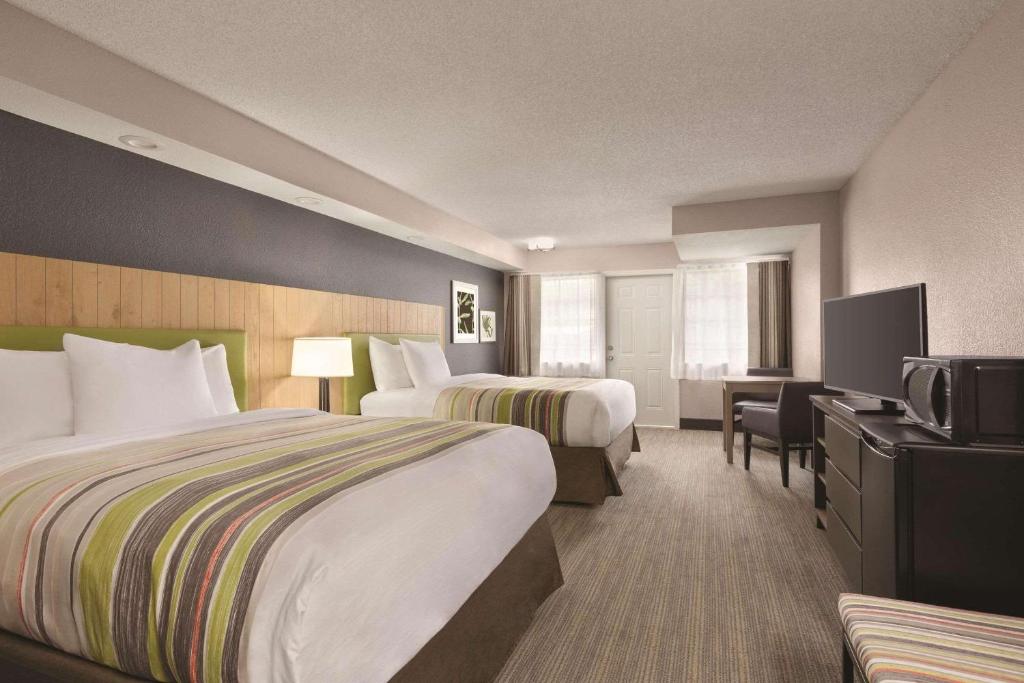 a hotel room with two beds and a television at Country Inn & Suites by Radisson, Pigeon Forge South, TN in Pigeon Forge