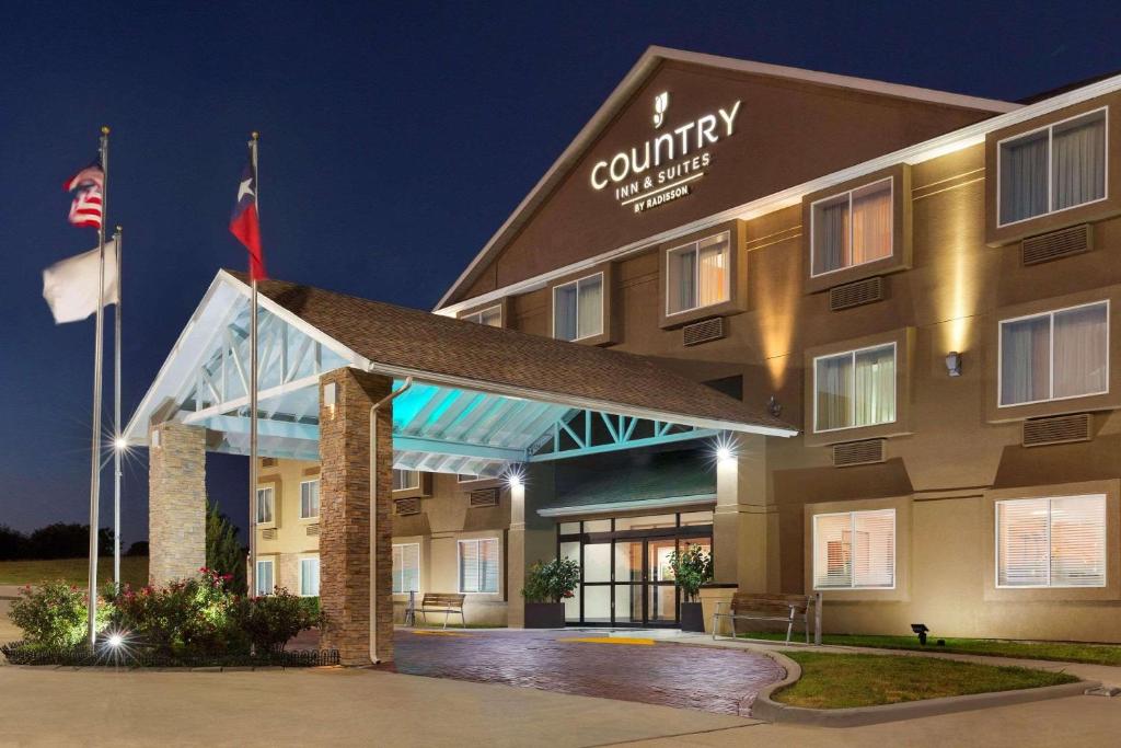 a front view of a hotel at night at Country Inn & Suites by Radisson, Fort Worth West l-30 NAS JRB in Fort Worth