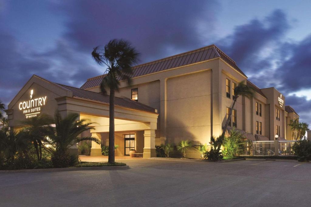 a building with a palm tree in front of it at Country Inn & Suites by Radisson, Portland, TX in Portland