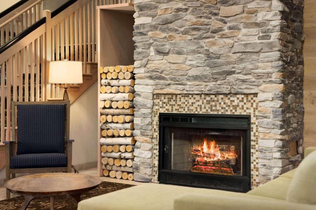 sala de estar con chimenea de piedra, sofá y mesa en Country Inn & Suites by Radisson, Williamsburg Historic Area, VA en Williamsburg