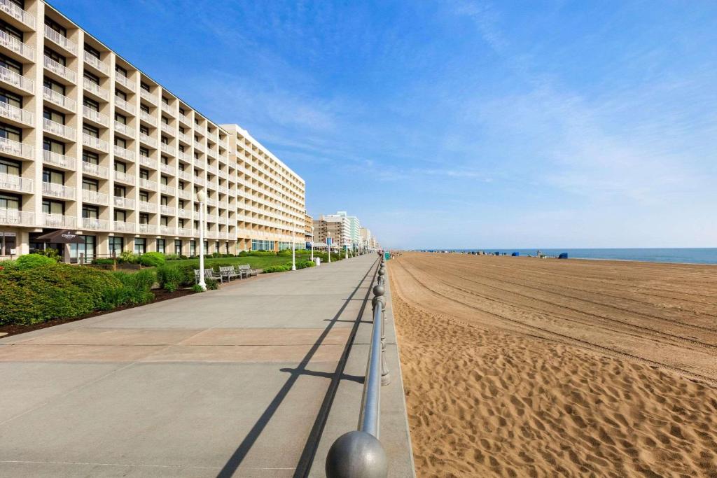 una playa de arena con un gran edificio y el océano en Country Inn & Suites by Radisson, Virginia Beach Oceanfront , VA, en Virginia Beach