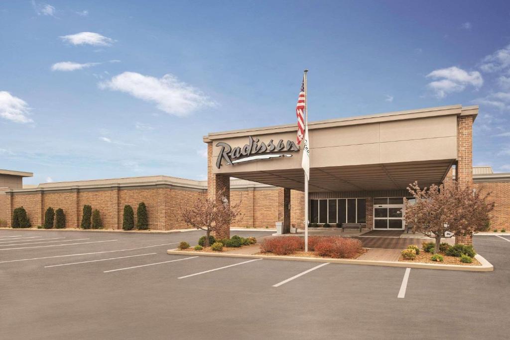 a dealership with an american flag in a parking lot at Radisson Hotel and Conference Center Fond du Lac in Fond du Lac