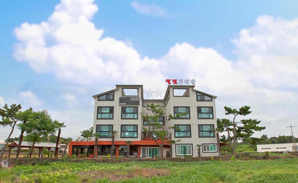 a large white building on top of a field at Starlight drops Pension in Jeju