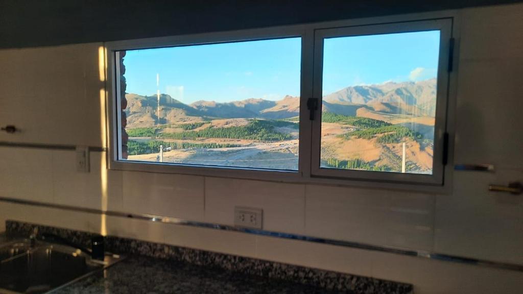 a bathroom window with a view of the mountains at Cabañas Millaray in Huinganco