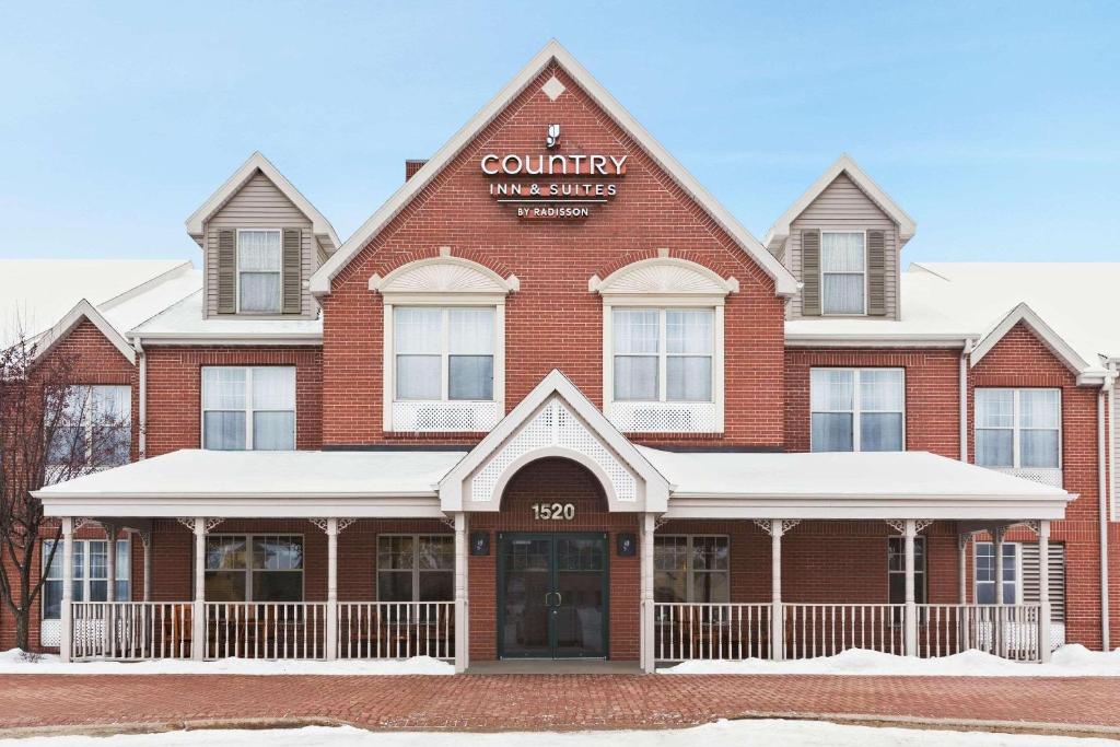 a large red brick building with a sign on it at Country Inn & Suites by Radisson, Wausau, WI in Schofield