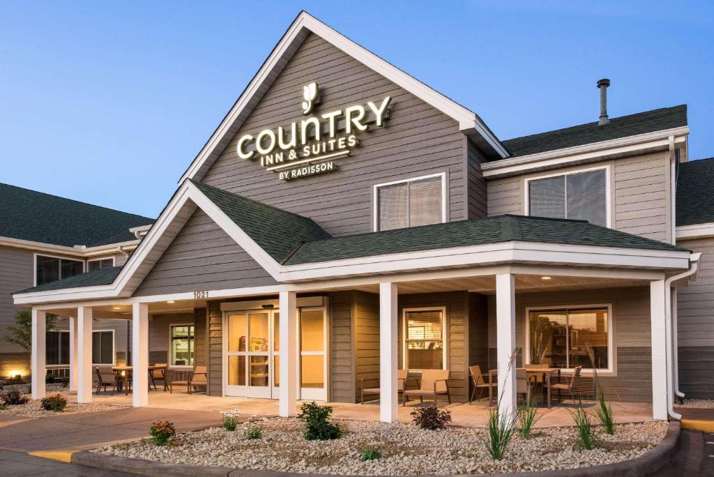 Country Inn & Suites by Radisson, Chippewa Falls, WI في شبوا فولز: مبنى نزل واجنحه ريفيه مع طاولات وكراسي