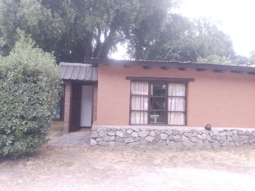 una pequeña casa con una pared de piedra y una ventana en Cabañas Lamani en Lago Puelo