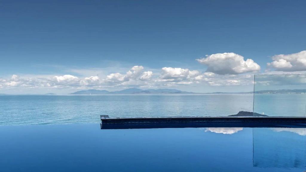 een zwembad met uitzicht op de oceaan bij Beachfront - Nelly Bay Apartment in Nelly Bay