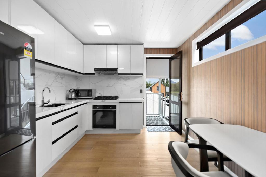 a kitchen with white cabinets and a table with chairs at The Headley Loft in Queenstown