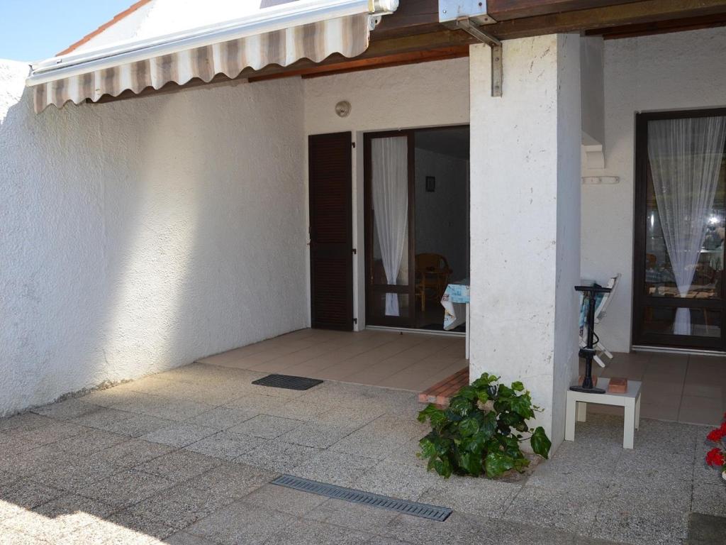 une maison blanche avec une porte et une terrasse couverte dans l'établissement Maison familiale à deux pas de la plage, idéale pour 6 pers. avec terrasse à Saint Jean de Monts - FR-1-323-480, à Saint-Jean-de-Monts