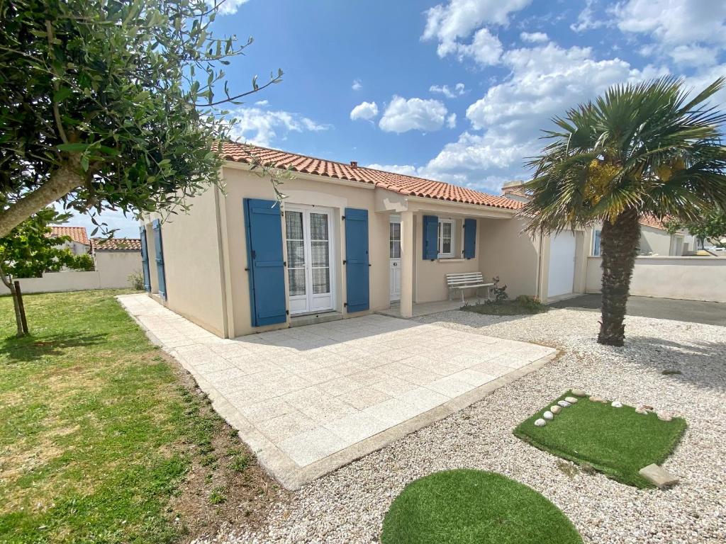 une maison avec une porte bleue et un palmier dans l'établissement Maison conviviale près de la plage avec jardin clos, 2 chambres, animaux admis - FR-1-231-299, à Bretignolles-sur-Mer