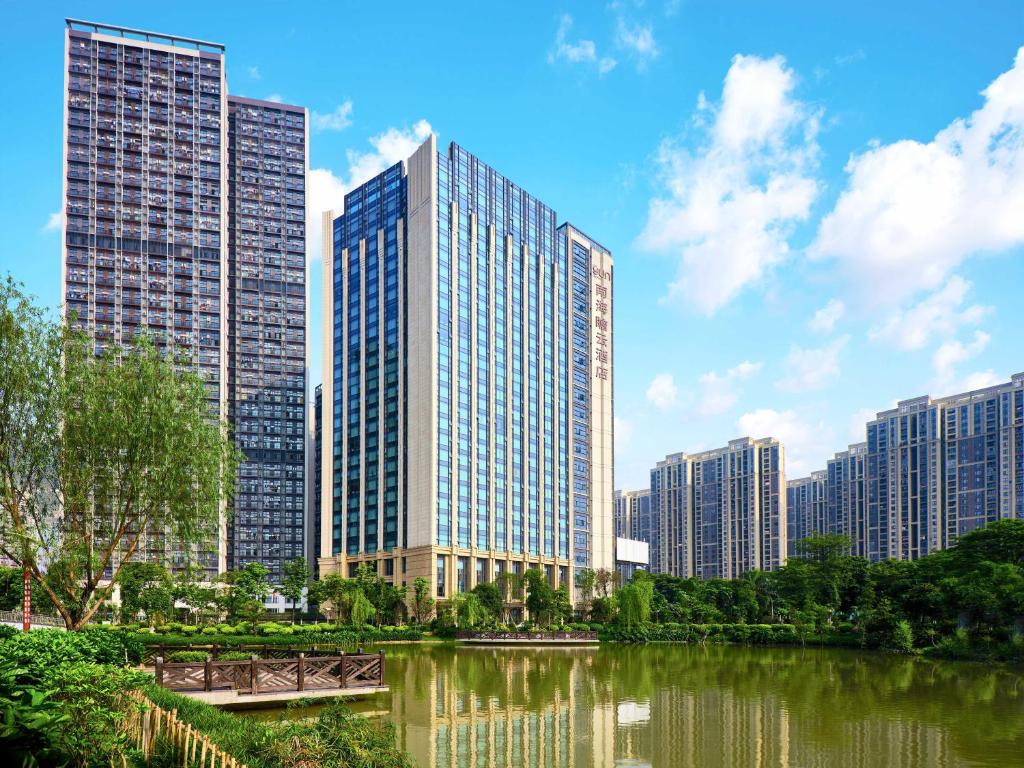 The Yun Hotel Foshan Nanhai في فوشان: أفق المدينة مع المباني الطويلة والنهر
