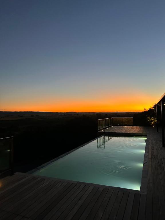 una piscina con puesta de sol en el fondo en Casa de campo altos de salamanca en Aiguá