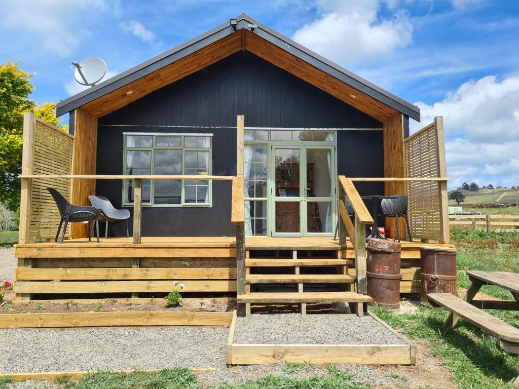 ein winziges Haus mit einer Veranda und einer Treppe in der Unterkunft Franvannah Cabin in Waihi