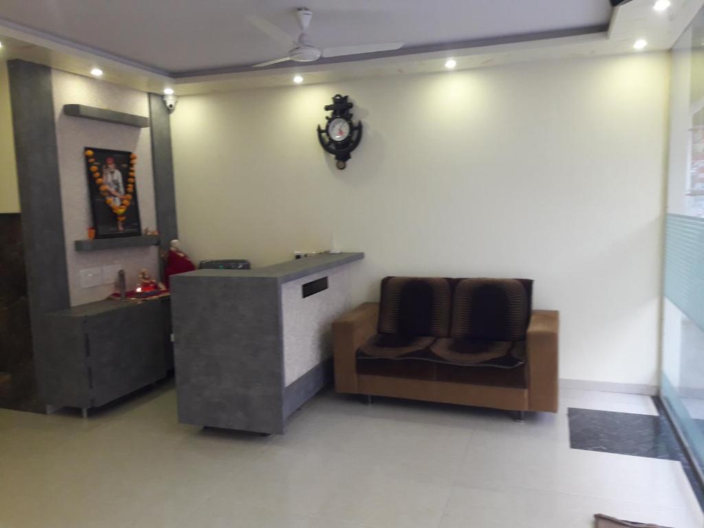 a waiting room with two chairs and a clock on the wall at HOTEL SAI MEERA PALACE in Shirdi