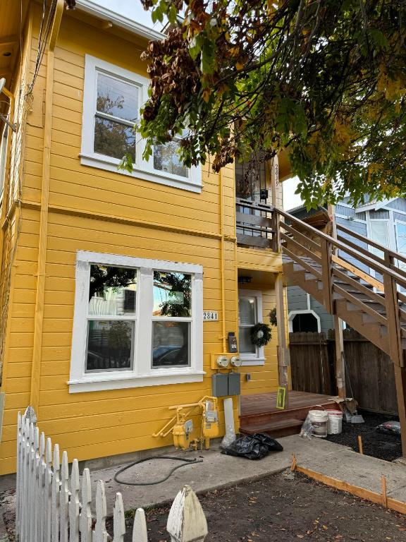 Casa amarilla con ventanas blancas y escalera en Bumblebee House en Oakland