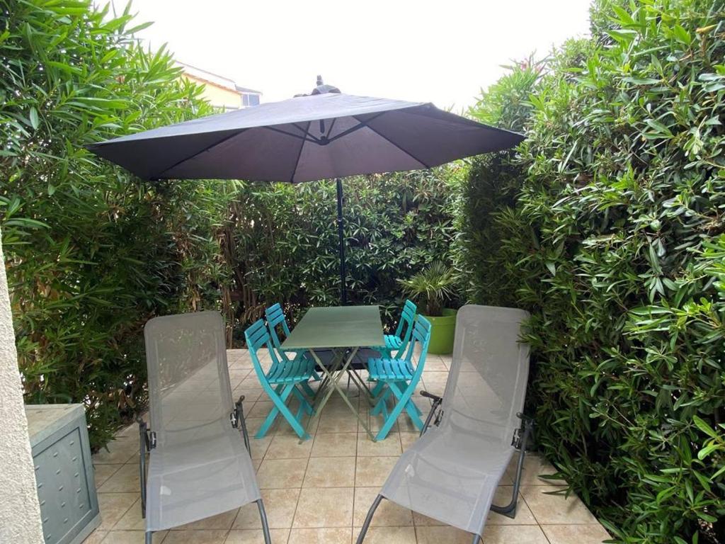- une table et des chaises sous un parasol sur la terrasse dans l'établissement À 5 min de la plage, terrasse cosy, appart moderne proche du centre et port - Cap d'Agde - FR-1-723-119, au Cap d'Agde