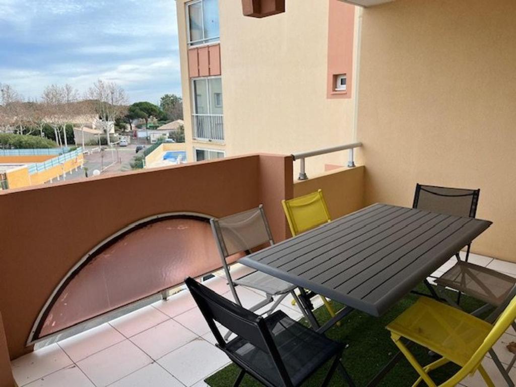 une table et des chaises sur le balcon d'un bâtiment dans l'établissement Appartement T2 cabine - Proche plage, commerces et piscine sécurisée - FR-1-749-35, au Cap d'Agde