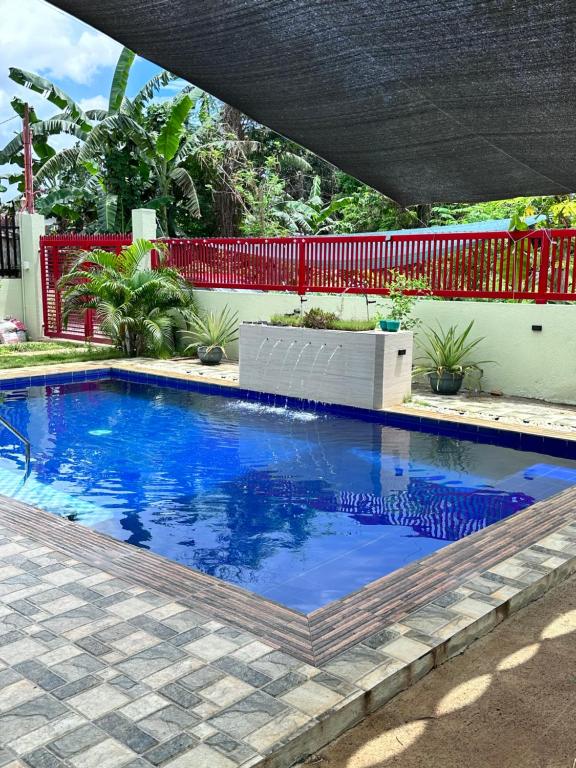une grande piscine bleue avec une clôture rouge dans l'établissement Clubmiller Guesthouse, à Puerto Princesa