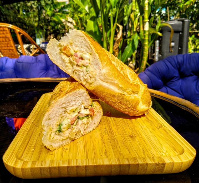 een sandwich doormidden gesneden op een houten snijplank bij The Mango Tree Guesthouse in Kampot