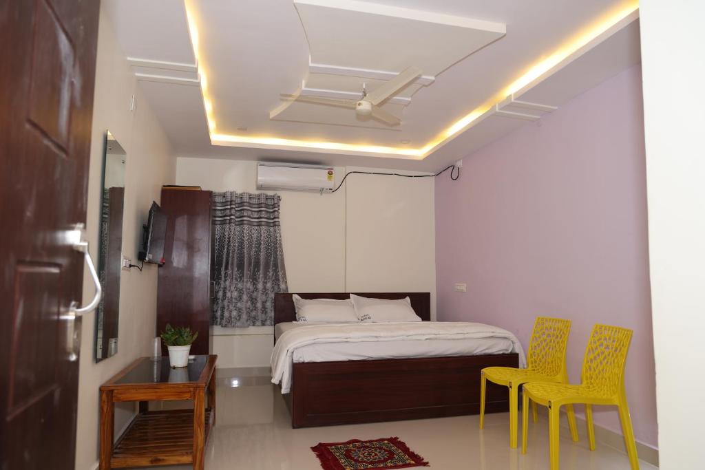 um quarto com uma cama e 2 cadeiras amarelas em Royal Stay Inn em Simhāchalam