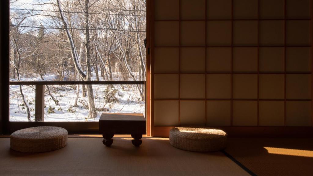 a room with a window with a table and two seats at Woody Island in Hakuba