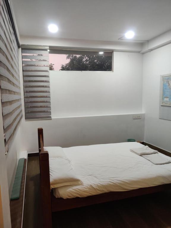 um quarto branco com uma cama e uma janela em Laasya Vilaasa em Mangalore