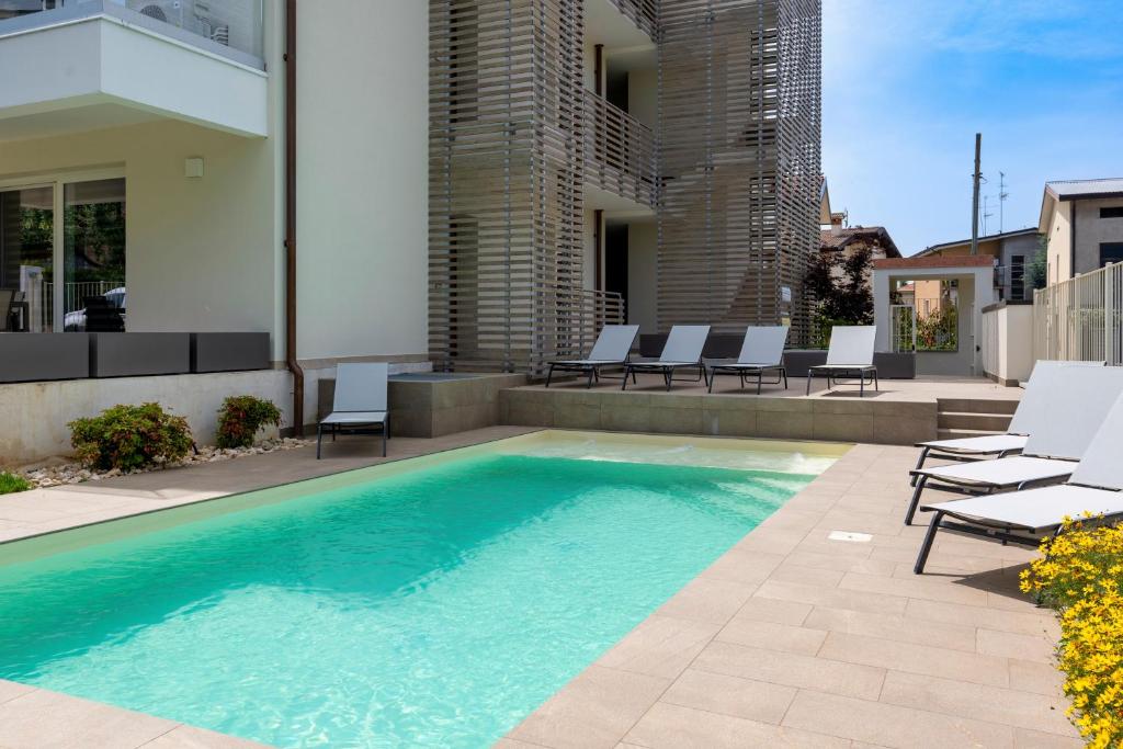 una piscina en un patio con sillas y un edificio en MALVEZZi Apartments, en Desenzano del Garda