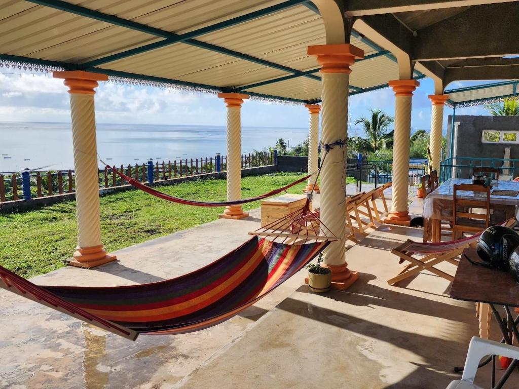 a hammock on a porch with the ocean in the background at Chez Tonio Magic Ocean View in Rodrigues Island