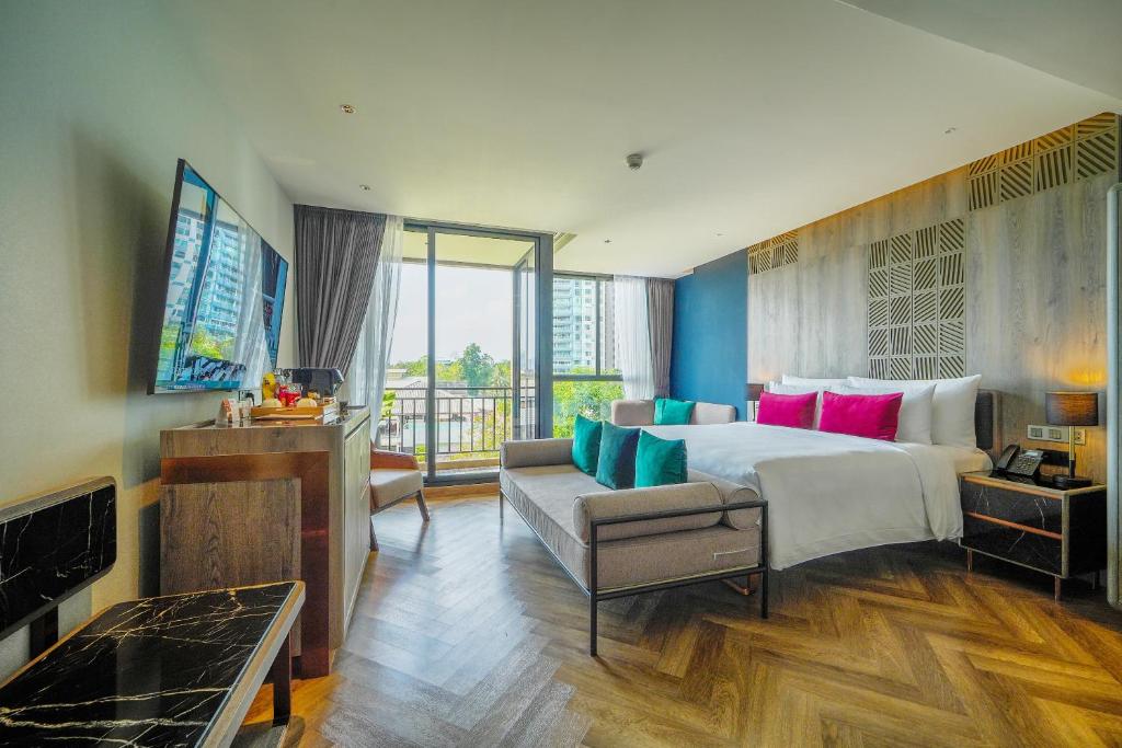 A spacious-looking suite-style room opens toward a balcony and city-facing windows.