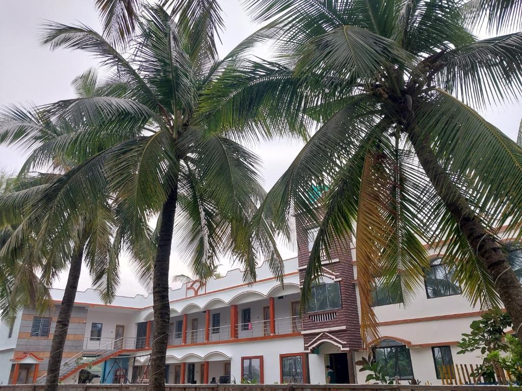 twee palmbomen voor een gebouw bij SURYA VILLA GUEST HOUSE in Tajpur