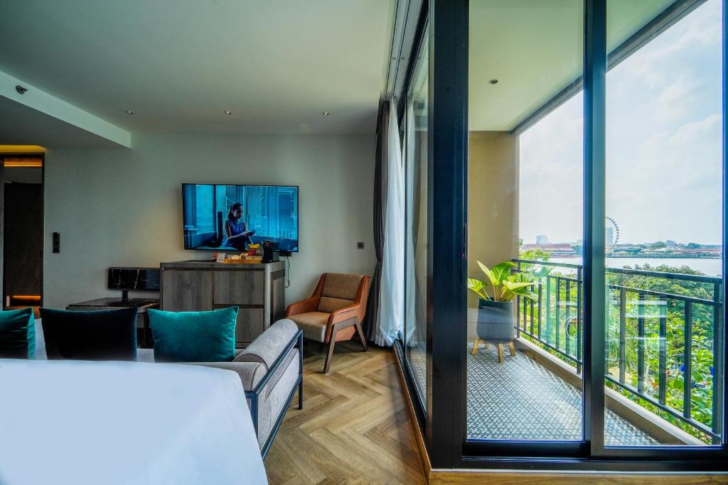A bright room with a living area, television and balcony overlooking the river and city.