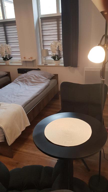 a living room with a table and a bed at Komfortowy apartament w centrum Nowego Sącza in Nowy Sącz