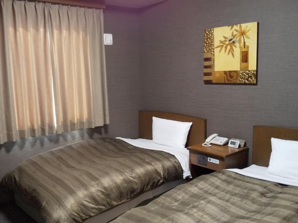 a hotel room with two beds and a window at Hotel Route-Inn Tsu Ekiminami -Kokudo23gou- in Tsu