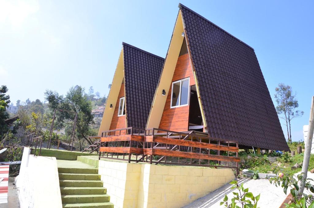 una casa con techo de paja y escaleras en Dollies Mountain View en Kodaikānāl
