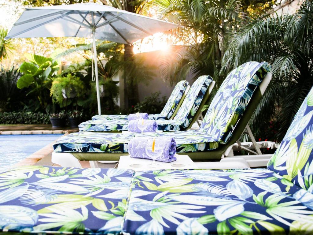 a group of lounge chairs with an umbrella next to a pool at Familia Guesthouse in Groblersdal