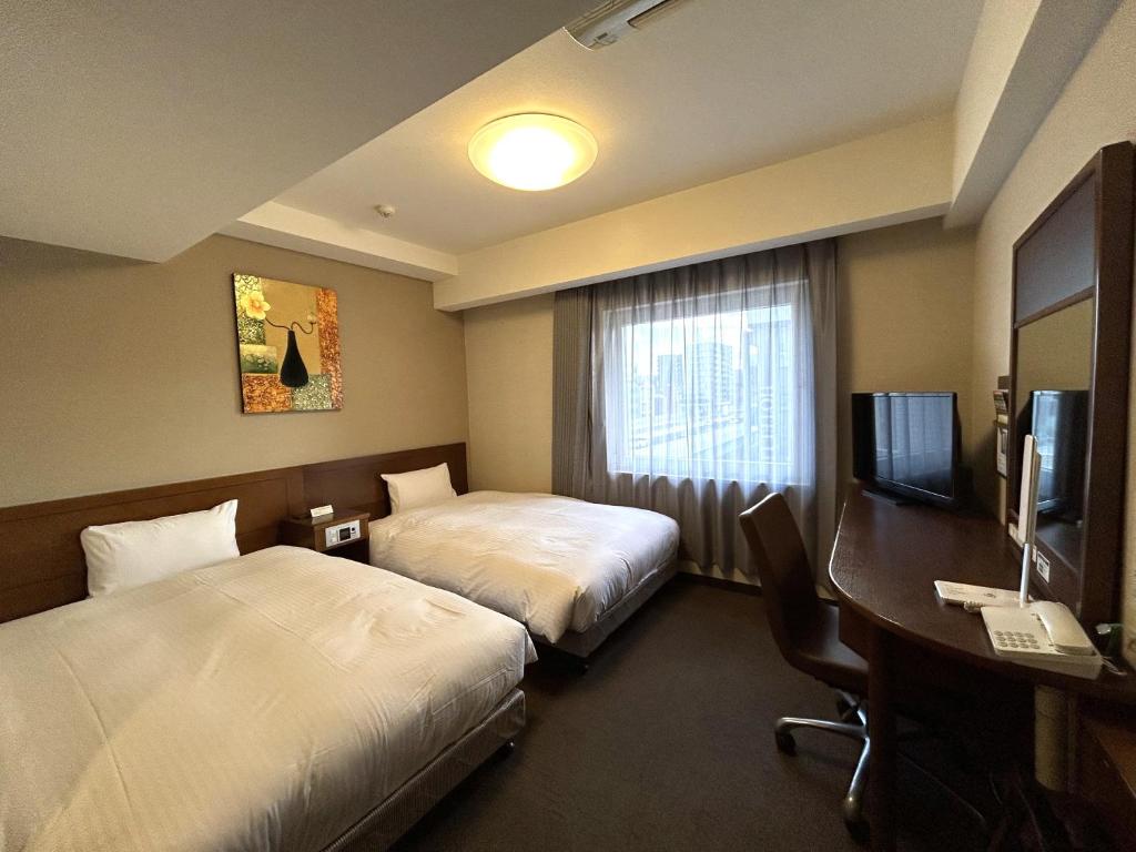 a hotel room with two beds and a desk and a television at Hotel Route-Inn Nagoya Sakae in Nagoya