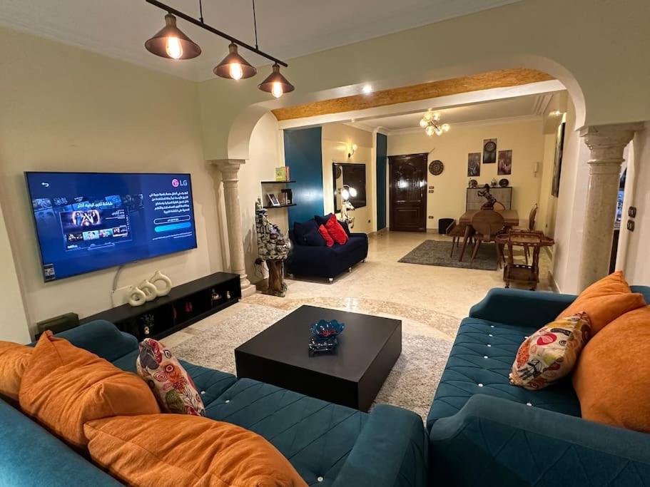 uma sala de estar com um sofá azul e uma televisão de ecrã plano em The Paradise Luxury Apartment no Cairo