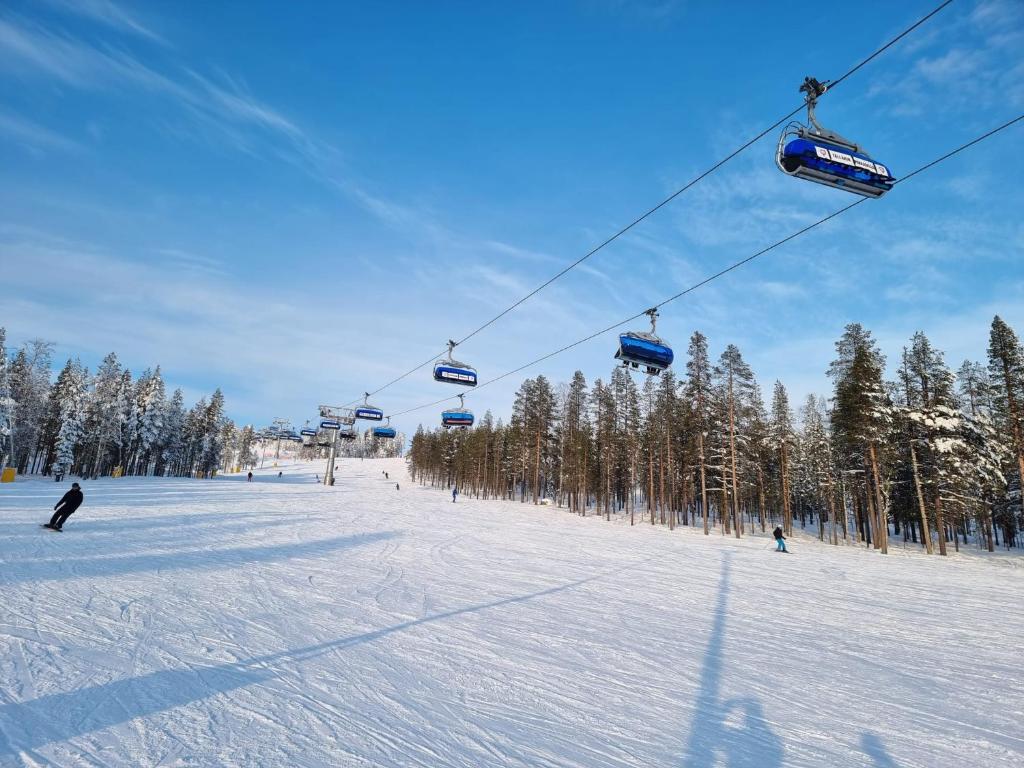 a ski lift with people skiing on a snow covered slope at Levi -Sky Slope Apartment - 3 Bedrooms in Sirkka
