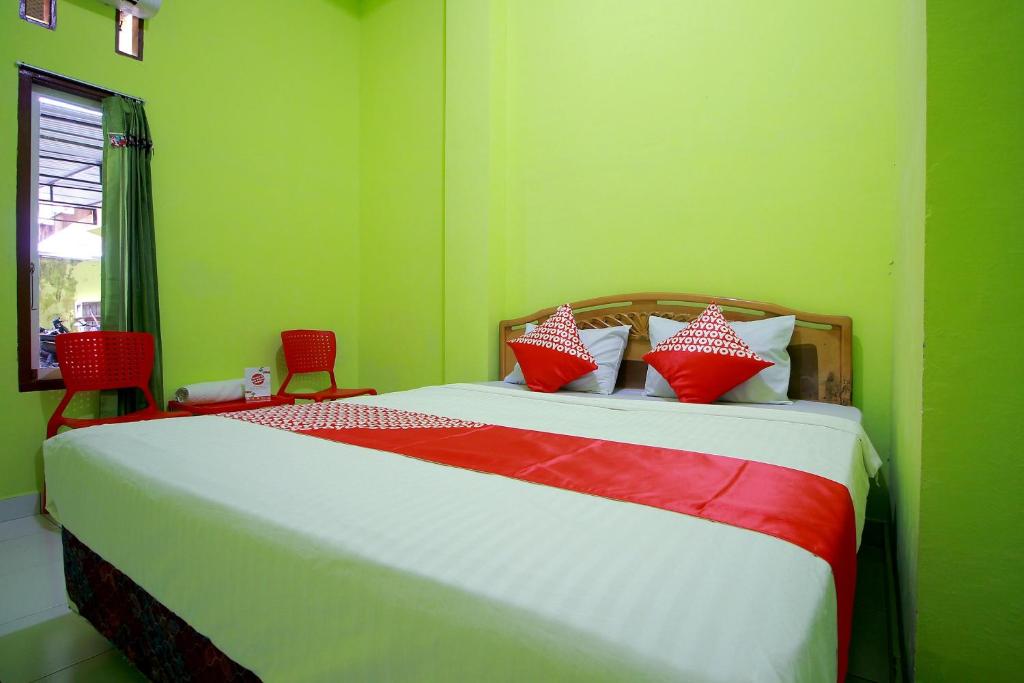 a bedroom with a bed with red and white pillows at OYO 2585 Sherren Guest House in Lubuklinggau