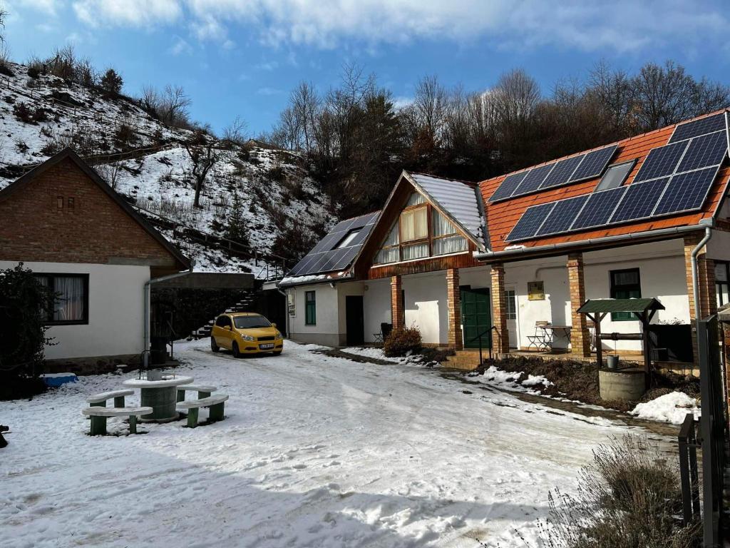 ein Haus mit Sonnenkollektoren auf dem Dach im Schnee in der Unterkunft Boróka Vendégház in Matrakeresztes