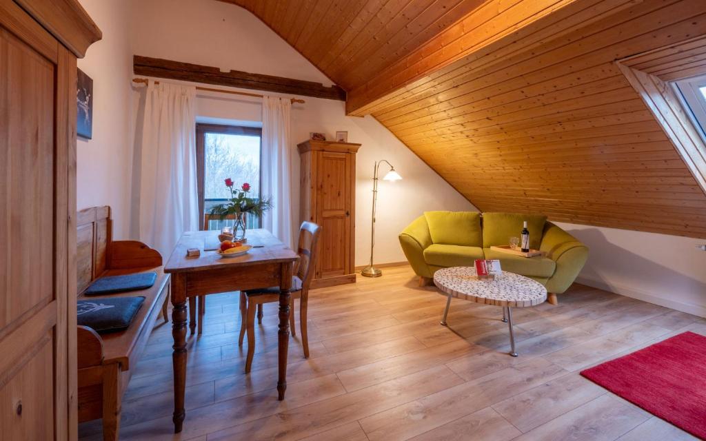ein Wohnzimmer mit einem grünen Sofa und einem Tisch in der Unterkunft Ferienwohnung „Rose“ in Wiesenfelden