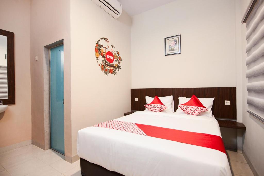a bedroom with a bed with red and white pillows at OYO 725 My Arm Home & Stay in Medan