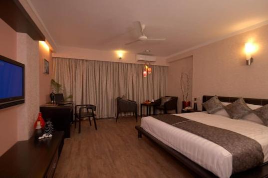 ein Hotelzimmer mit einem Bett und einem Wohnzimmer in der Unterkunft Aec Travels and Leisure Solution Pvt Ltd in Alappuzha
