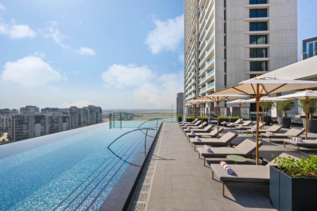 ドバイにあるPalace Dubai Creek Harbourのラウンジチェアとパラソル付きのスイミングプールを併設しています。