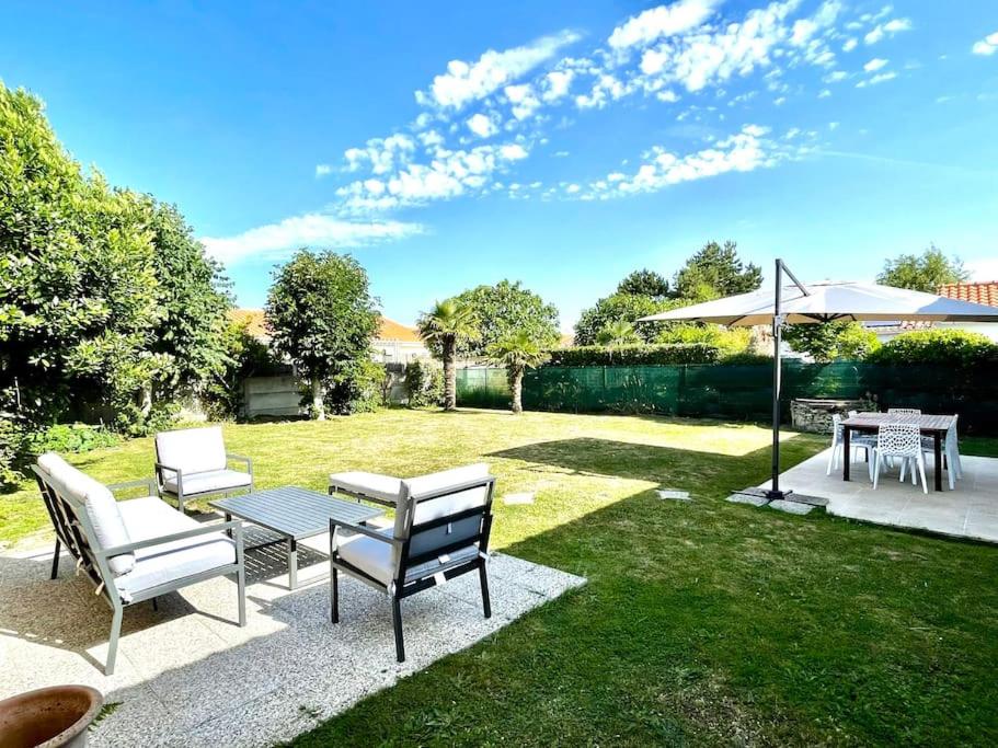 un patio avec deux chaises, une table et un parasol dans l'établissement Charmante Maison à la mer proche plage, à Saint-Hilaire-de-Riez