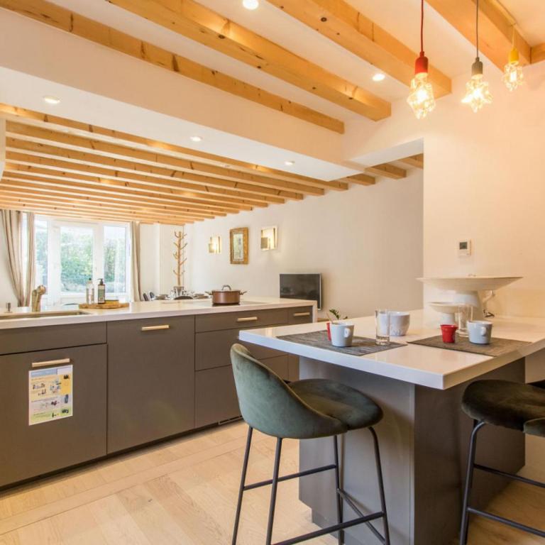 une cuisine avec un grand îlot et deux tabourets de bar dans l'établissement Duplex les Glycines, à Écharvine