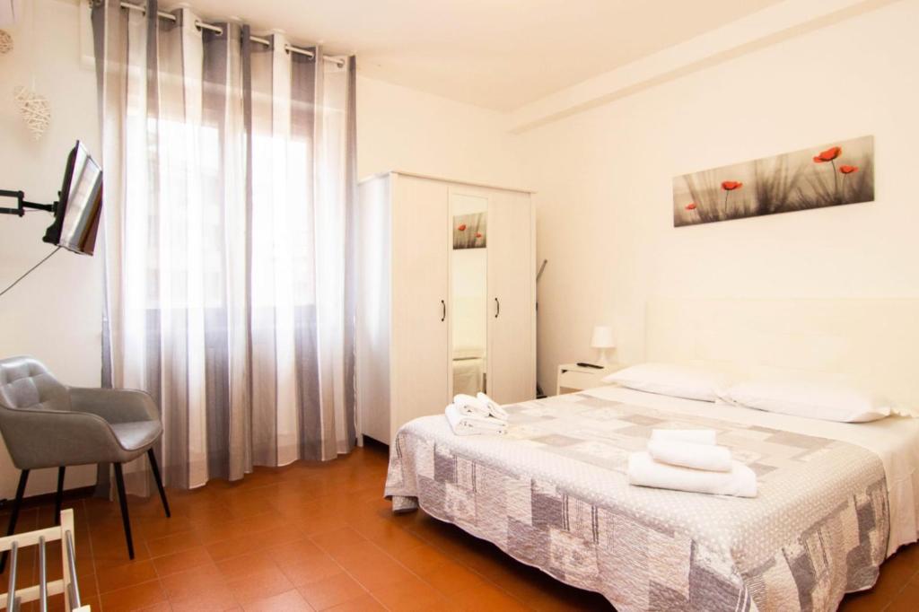 a white bedroom with a bed and a chair at Casa Vacanze Tosca 3 in Pisa